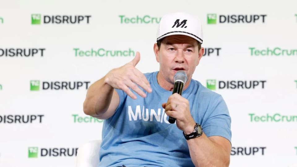 Mark Wahlberg speaking into a microphone on the TechCrunch Disrupt stage.