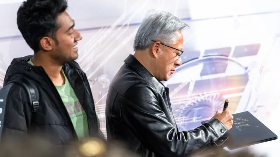 Jensen Huang signing a laptop beside an attendee at an RTX Spark launch event.